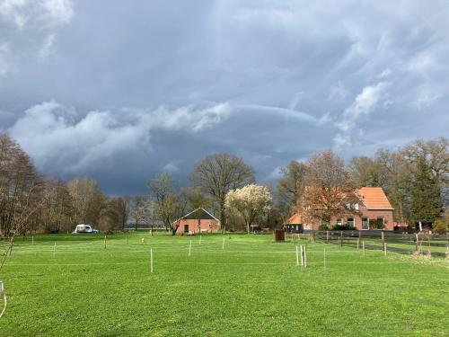 a green field with houses and a cloudy sky at Hoeve de Snippert in Groenlo