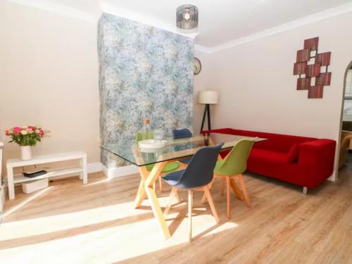 a living room with a glass table and a red couch at Llandudno 3 Bedroom Holiday Apartment in Town Centre in Llandudno