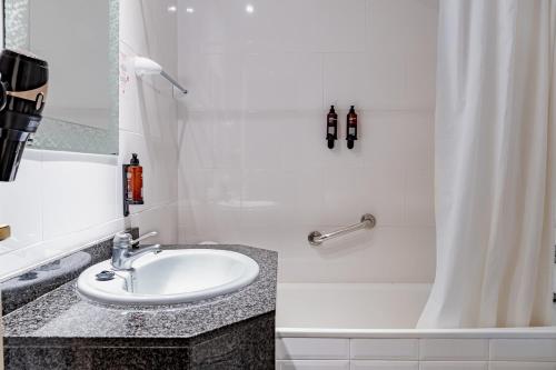 a white bathroom with a sink and a shower at 30º Hotels - Hotel Espanya Calella in Calella