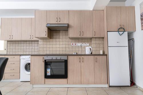 a kitchen with wooden cabinets and a washer and dryer at Private room in shared flat in Nicosia
