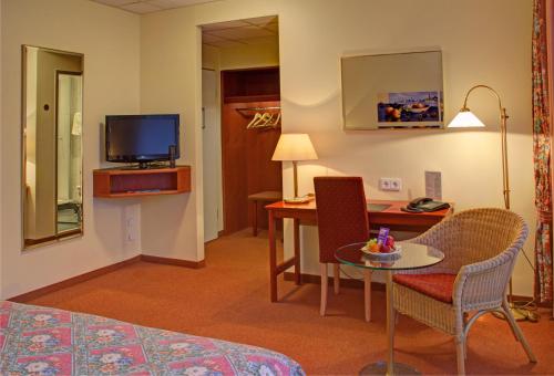 a hotel room with a bed and a table and a television at Hotel Kreuzer in Wedel