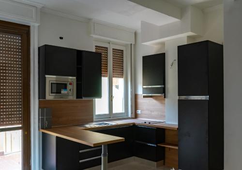 a kitchen with black cabinets and a microwave at PALAZZO NOVECENTO Rooms in Lecco