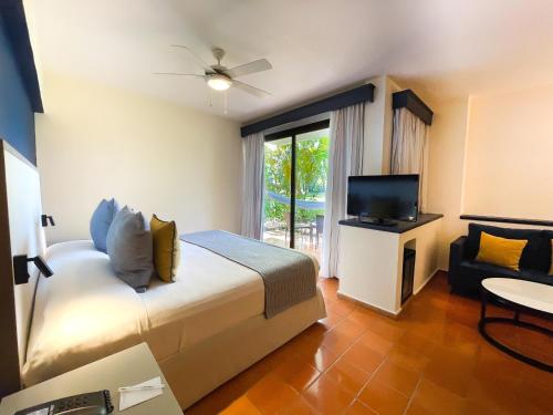 a bedroom with a bed and a television and a chair at Catalonia Punta Cana - All Inclusive in Punta Cana