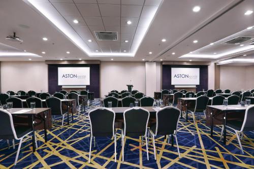 a conference room with tables and chairs and two screens at Aston Anyer Beach Hotel in Anyer