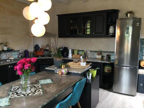 una cocina con nevera y una mesa con flores. en Maison cosy à la campagne en Montpeyroux