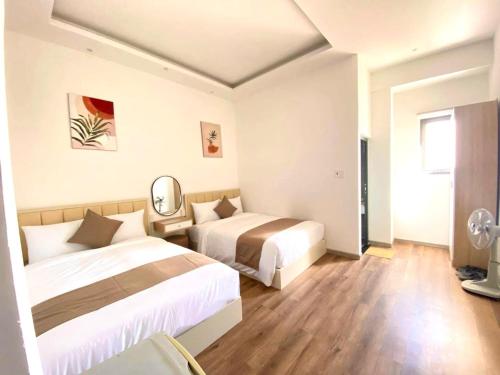 a hotel room with two beds and a mirror at Torino Hotel Dalat in Da Lat