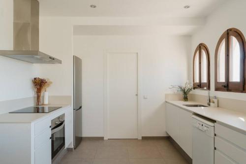 una cocina blanca con armarios blancos y fregadero en La Pomera, en Ultramort