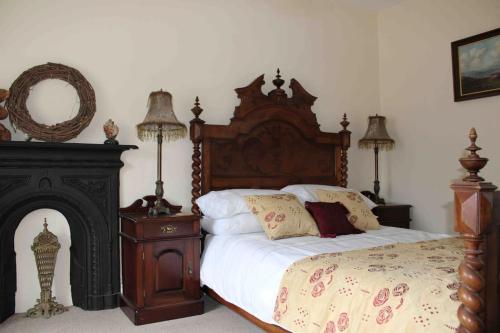 a bedroom with a bed with a wooden headboard and a fireplace at Ivy House in Bangor