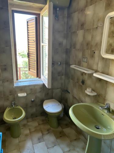 ein Bad mit 2 Waschbecken, einem WC und einem Fenster in der Unterkunft Casa vacanze Marina di Camerota in Marina di Camerota