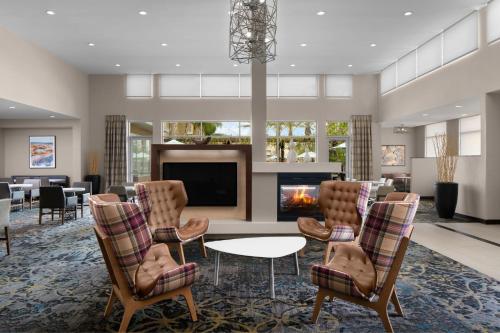 a living room with a fireplace and chairs and a tv at Residence Inn by Marriott Tustin Orange County in Tustin