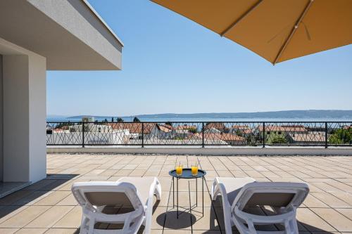 two white chairs and a table on a patio with the ocean at Penthouse Apartments East and West Star in Kaštela