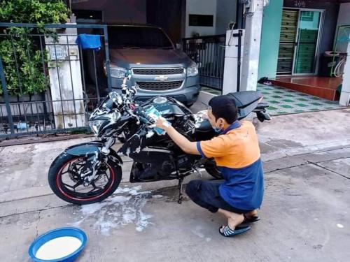 Un uomo sta lavando una moto per strada di บ้านสวนเนินเห็ด a Chanthaburi