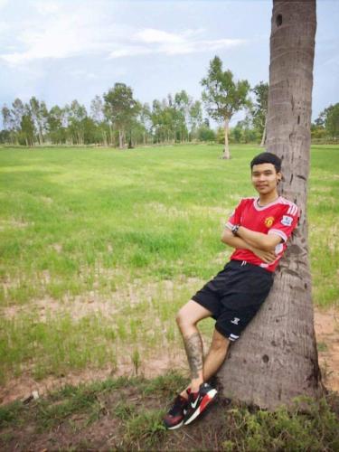 a young man sitting on the side of a tree at บ้านสวนเนินเห็ด in Chanthaburi