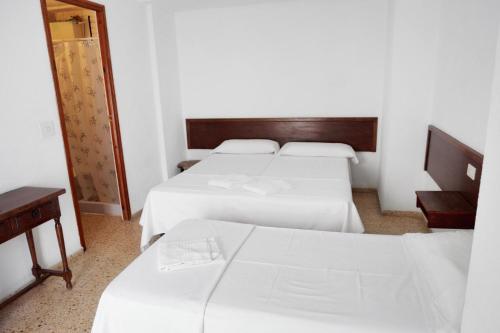 Habitación de hotel con 3 camas y espejo en Hostal La Torre, en Benicàssim