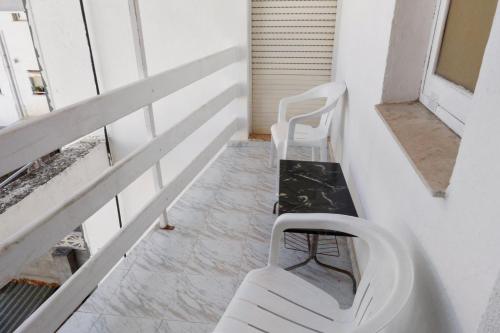 a balcony with two white chairs and a bench at Hostal La Torre in Benicàssim