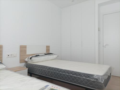 2 camas en una habitación con paredes blancas en Residencial El Trenet 2 B, en Benicàssim