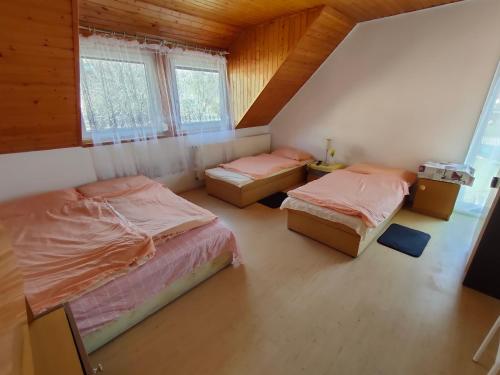 a bedroom with two beds and two windows at Malom-tavi vendeghaz in Tapolca