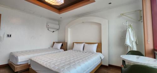 a bedroom with two beds and a table and a window at Namhae Beach Hotel in Namhae