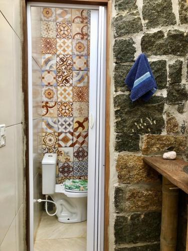 a bathroom with a toilet and a stone wall at Sitio Simple Life in Ubatuba