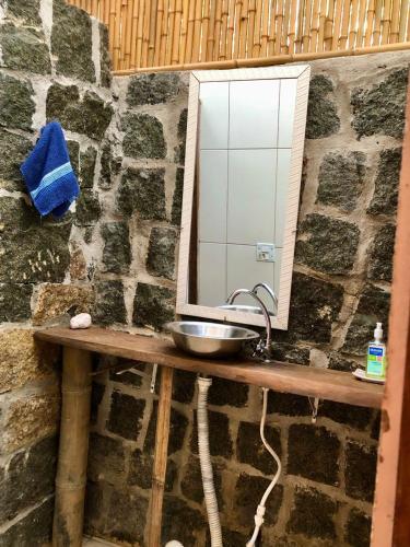 a bathroom with a sink and a mirror on a stone wall at Sitio Simple Life in Ubatuba