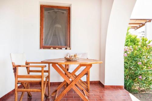 drewniany stół i 2 krzesła na patio w obiekcie Siroco Patmos Agriolivadi w mieście Patmos