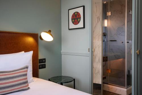 a bedroom with a bed and a glass shower at Maison Rouge Strasbourg Hotel & Spa, Autograph Collection in Strasbourg