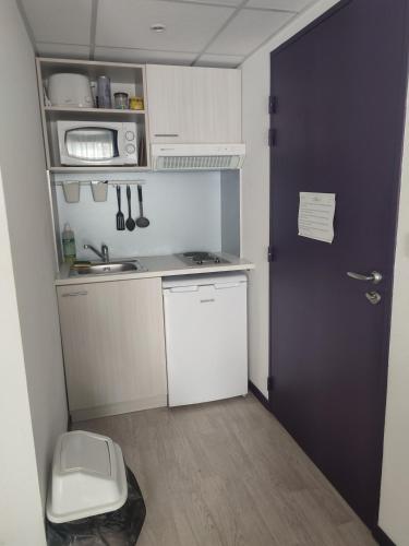 une petite cuisine avec un évier et une porte. dans l'établissement Résidence la closeraie, à Lourdes