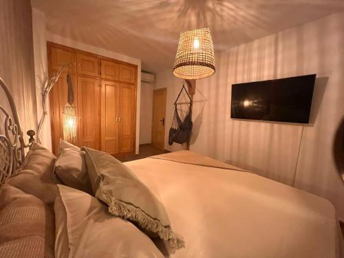 - une chambre avec un lit, une télévision et un lustre dans l'établissement Yanes Bed And Breakfast Ronda, à Ronda