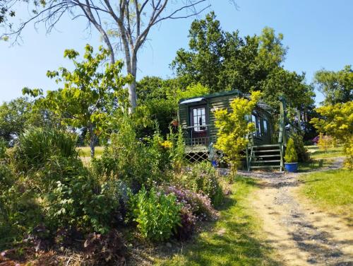 een klein huisje in een tuin met bloemen bij Peaceful ensuite lakeside cabin 'Tench' in Hadlow Down