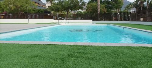 a swimming pool with blue water in a yard at Residencial El Trenet 2C in Benicàssim