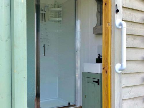 uma porta de vidro para uma casa de banho com um lavatório em Charming tranquil Shepherds Hut with lakeside balcony 'Roach' em Uckfield