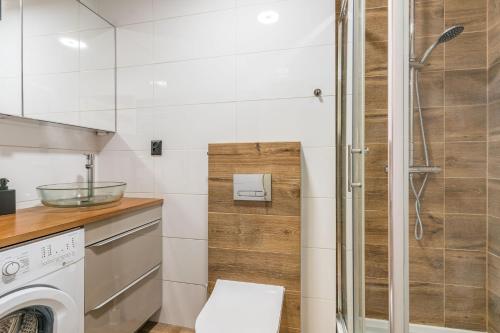 a bathroom with a shower and a washing machine at Apartament Black Stripes blisko morza in Gdańsk
