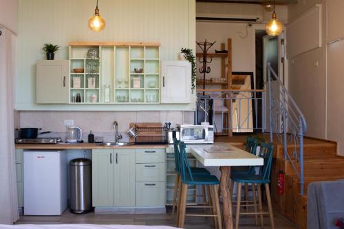 una cocina con armarios blancos y una mesa con sillas. en Harmony Inn, en Safed