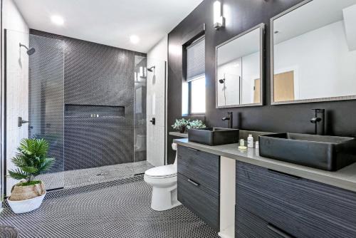 a bathroom with two sinks and a toilet and a shower at Eclipse Rooftop Villa in New Orleans