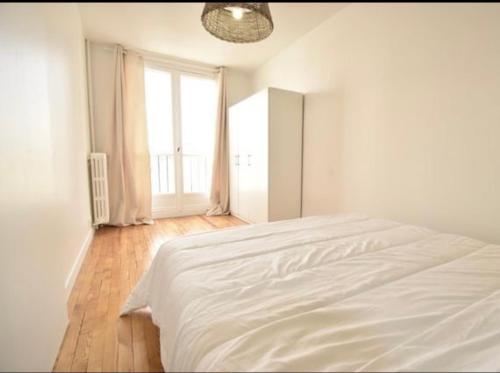 a white bed in a white bedroom with a window at Superbe appartement cosy Paris/Stade de France in Aubervilliers