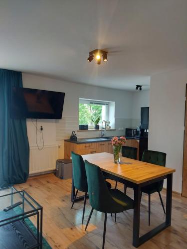 a kitchen with a wooden table and green chairs at Apartamenty nad jeziorem in Mikołajki