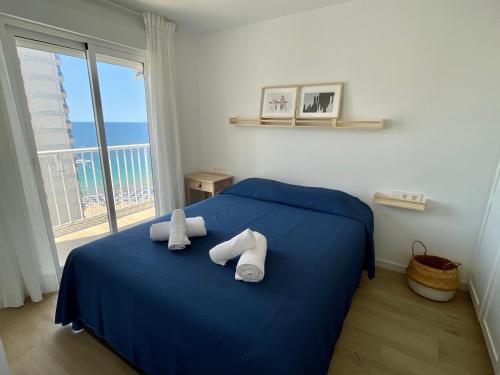 een slaapkamer met een blauw bed en een groot raam bij Apartamento turístico Playmon Bacana Planta 14 in Benidorm
