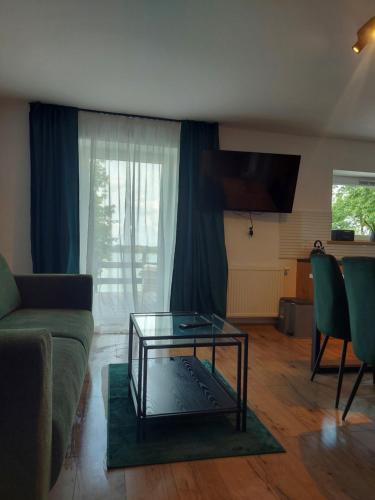 a living room with a couch and a glass table at Pokoje i apartamenty MatDar in Mikołajki