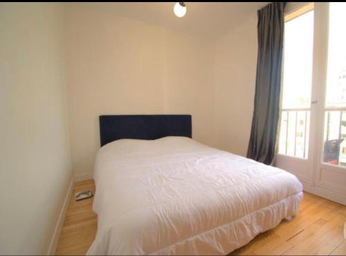 a white bed in a room with a window at Superbe appartement cosy Paris/Stade de France in Aubervilliers