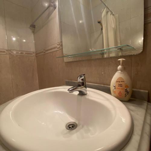 a white sink with a mirror and a bottle of soap at Apartamento Varanda do Sol in Amora