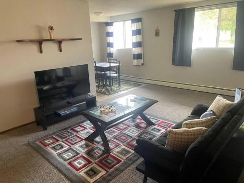 a living room with a tv and a coffee table at One Bedroom Main floor Apartment in Camrose