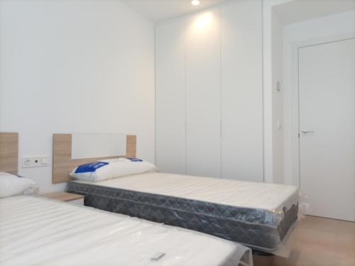 2 camas en una habitación con paredes blancas en Residencial El Trenet Ático-Duplex en Benicàssim
