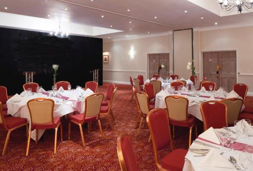 a conference room with tables and chairs and a projection screen at Holiday Inn Reading West by IHG in Reading