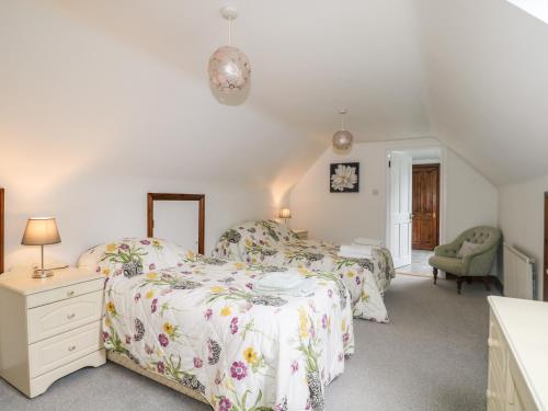 1 dormitorio con 2 camas y 1 silla en Miswells Cottages - Lake View, en Turners Hill