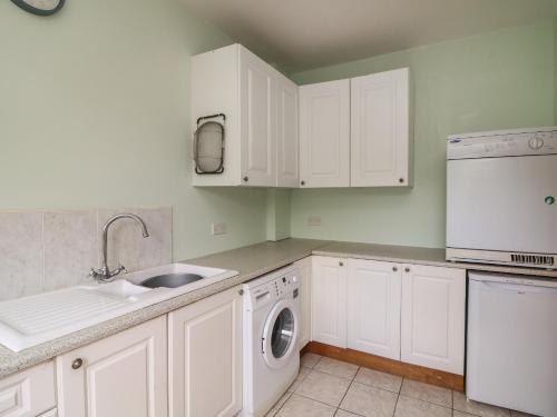 a kitchen with white cabinets and a sink and a dishwasher at Bolger House in Blackwater