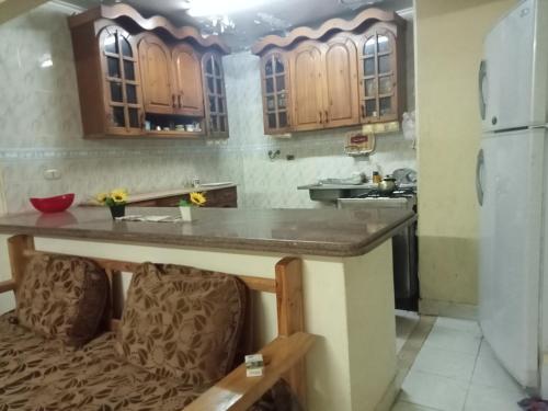 una cocina con armarios de madera y una encimera con 2 sillas en شاليه دور ارضى مدخل خاص يرى البحر en Qaryat Shurūq