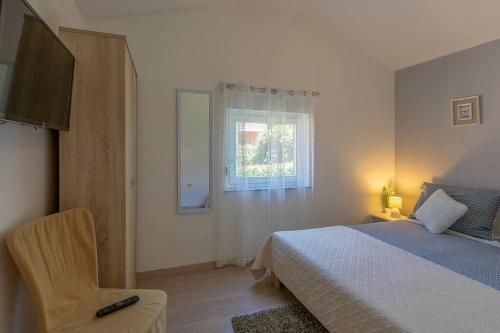 a bedroom with a bed and a chair and a window at Lovely guest house Veli Vrh in Pula