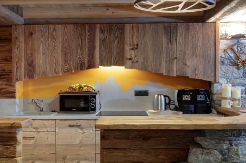 a kitchen with wooden cabinets and a microwave oven at Chalet Matterhorn Francois - Central Ski Chalet with SPA and Breakfast, 100mt lift in Breuil-Cervinia