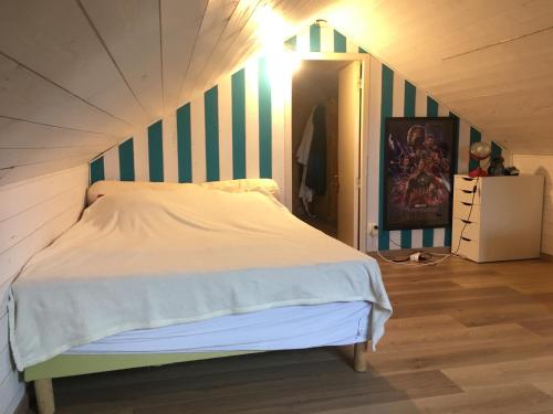 um quarto com uma cama com uma parede listrada em Maison entre mer et campagne em Landéda