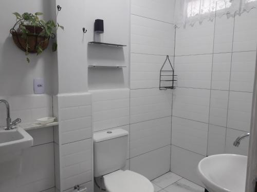a white bathroom with a toilet and a sink at Apartamento Gonzaga in Santos